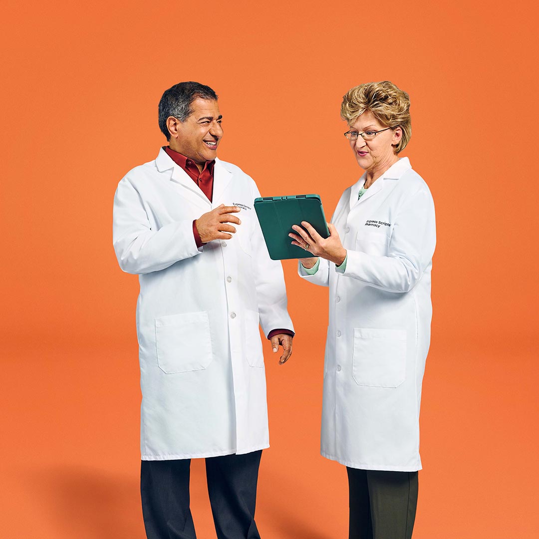 Two pharmacists with Express Scripts® Pharmacy look over a patient’s medication list on their tablet.Two pharmacists with Express Scripts® Pharmacy look over a patient’s medication list on their tablet.