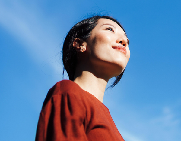 woman in red shirt smiling with a blue sky in the background